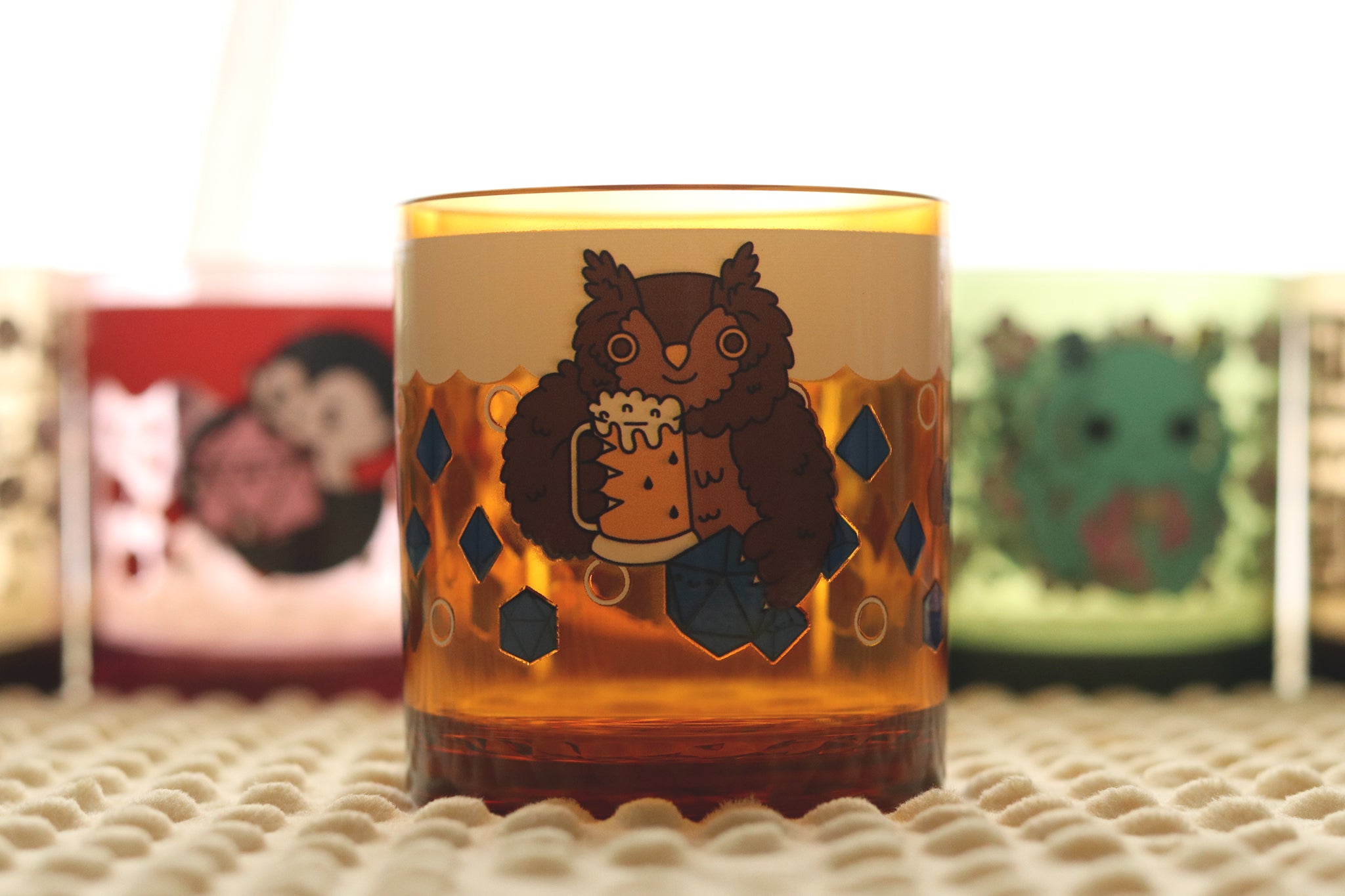 Amber-colored drinking cup featuring a cartoon owlbear character holding a beer stein in d20, surrounded by blue polyhedral dice and bubbles.