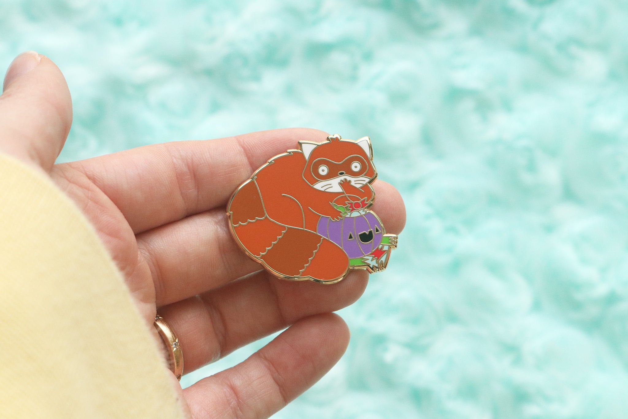 Red panda enamel pin. Critter is caught red-handed eating halloween candy out of a purple pumpkin basket.