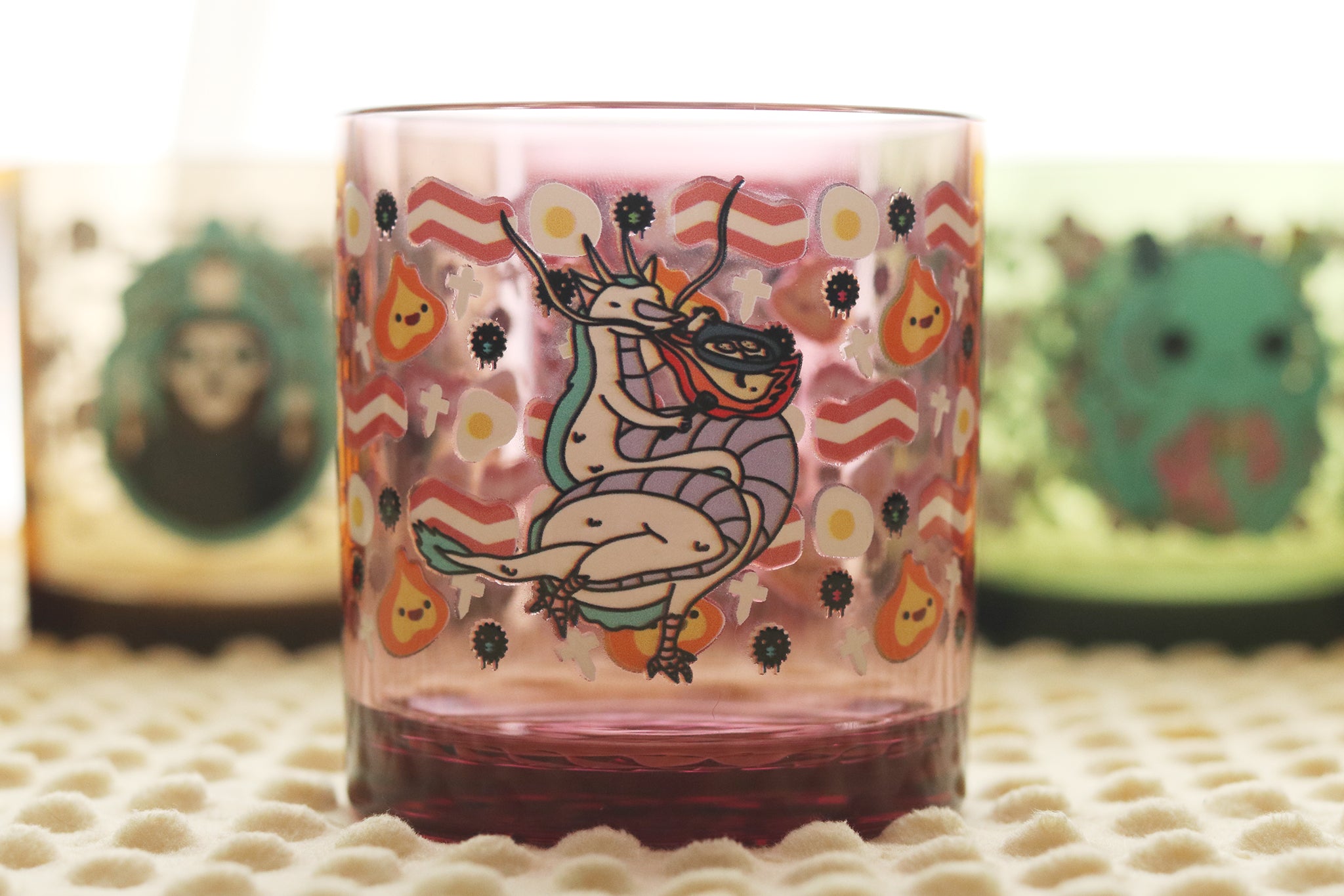 Dragon's Breakfast Tossware glass with whimsical dragon chef cooking eggs with his flaming breath photographed on a textured surface with blurred background