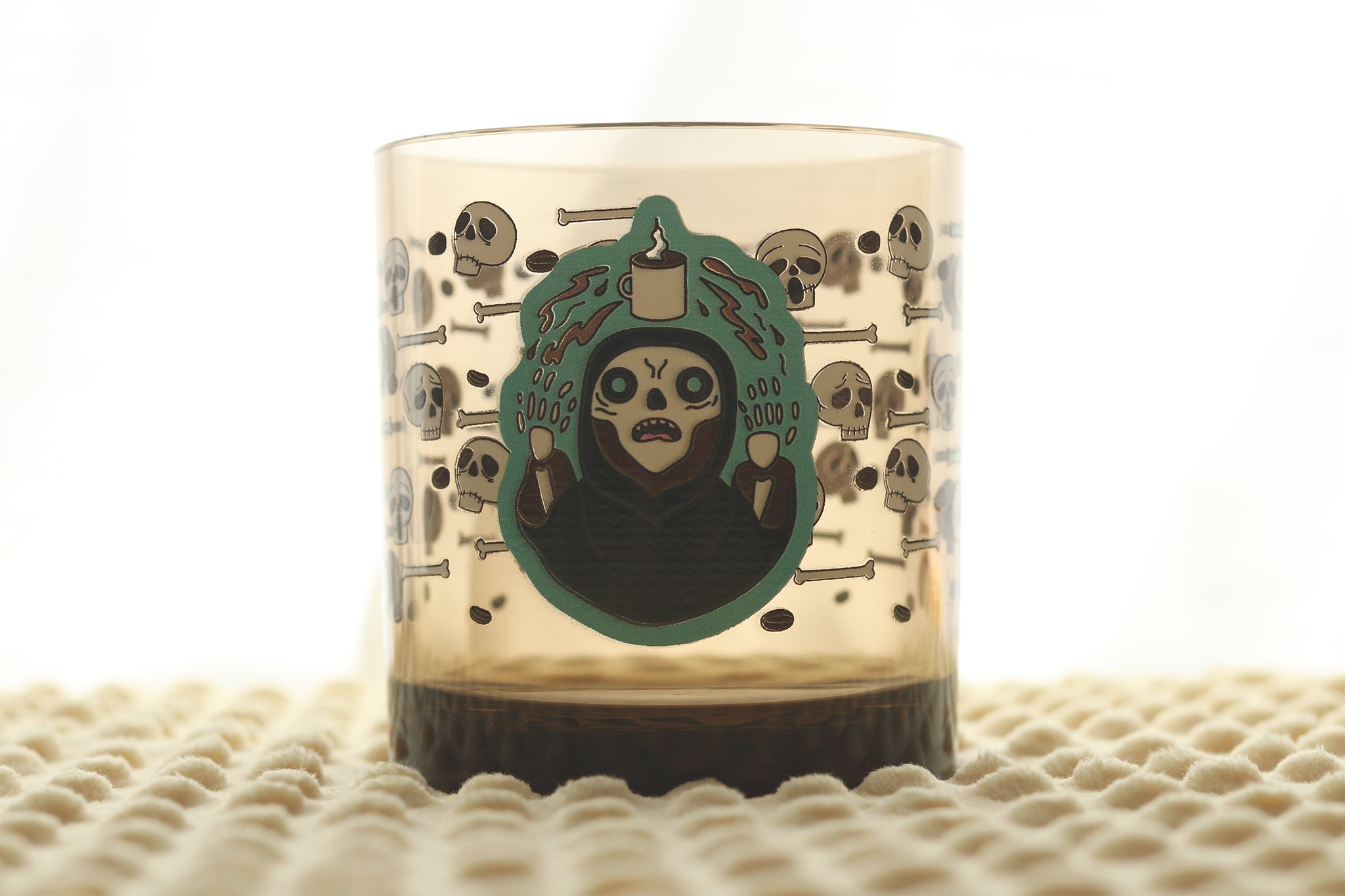Drinking cup featuring a lich character with glowing eyes surrounded by skulls and bones in a repeating pattern around the cup