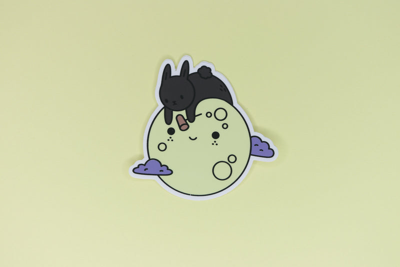 sticker of black rabbit on yellow moon with purple clouds