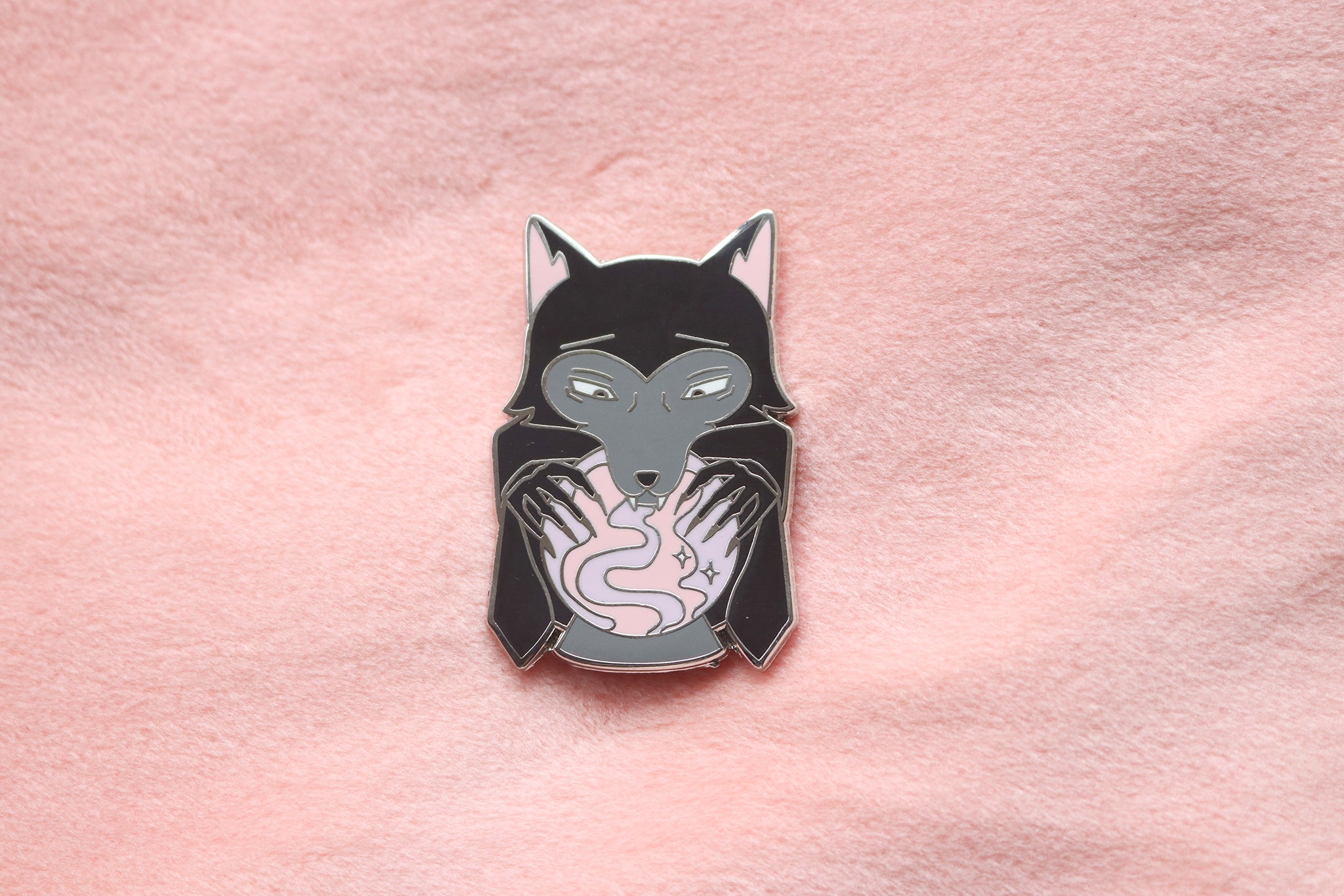Enamel pin of a black wolf looking into a pink and purple crsytal ball.