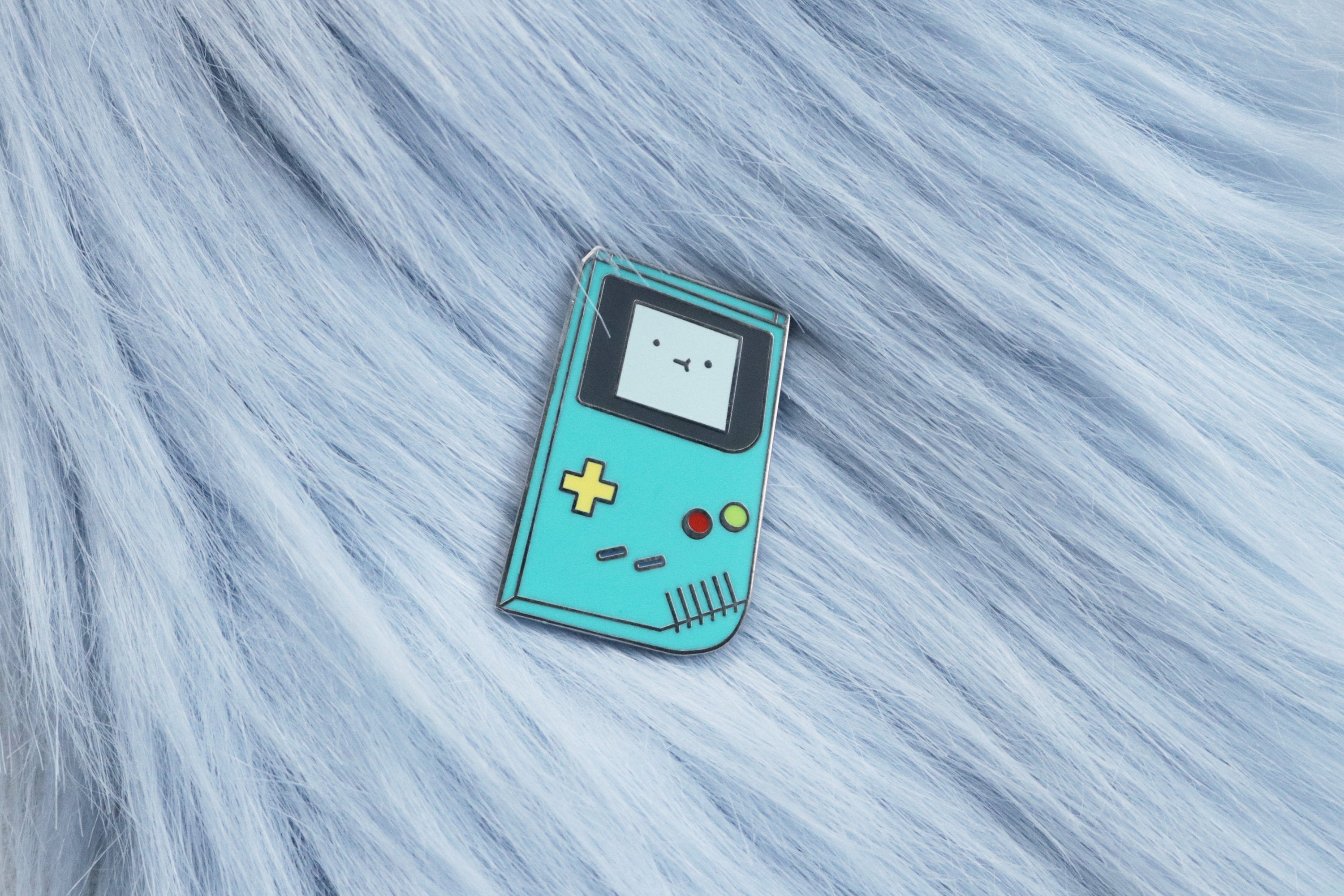 BMO from Adventure Time Inspired Game Boy Enamel Pin on Blue Fur Background