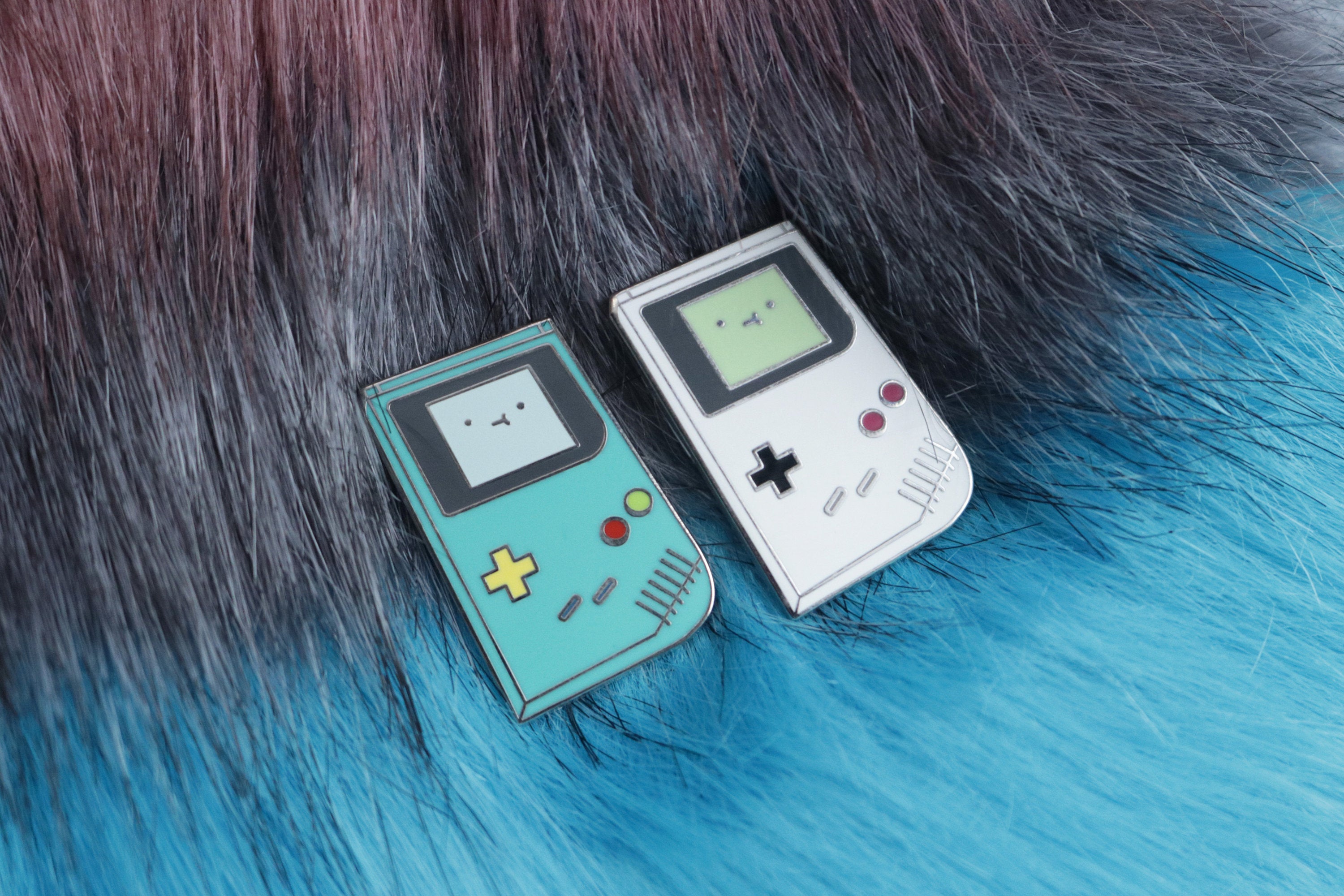 Teal and Gray Game Boy Hard Enamel Pins on Gray and Blue Fur Background