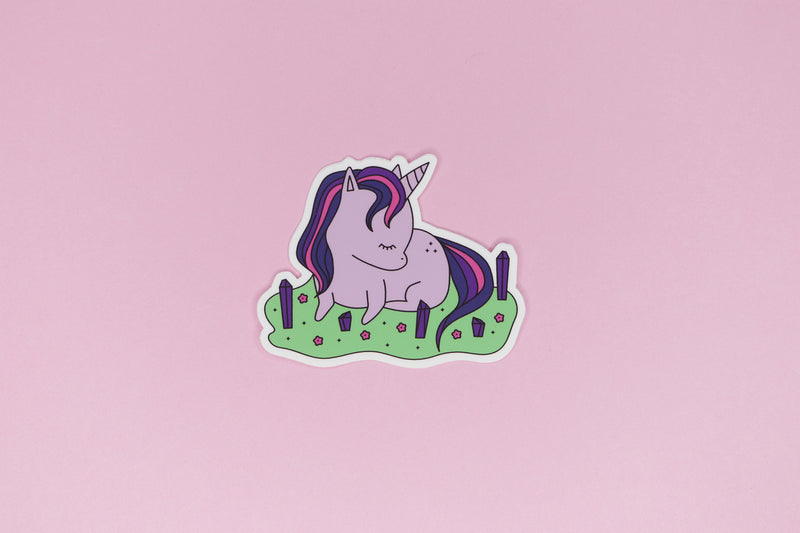 Sticker of Pink and Purple Unicorn laying in field of pink flowers and purple crystals