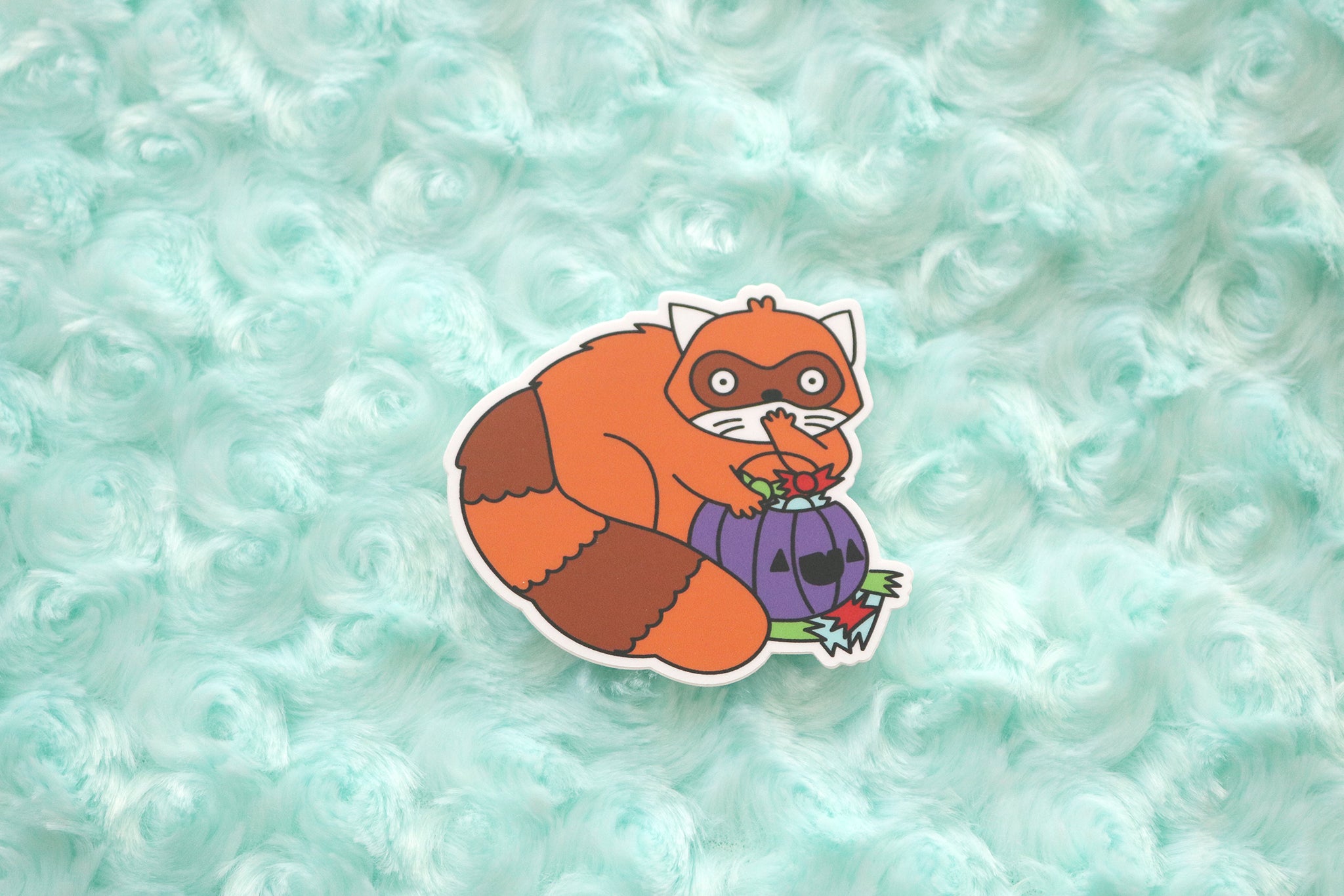 Red panda vinyl sticker shows a shocked looking trash gobbler shoving halloween candy in his mouth straight from a trick-or-treaters candy bucket.